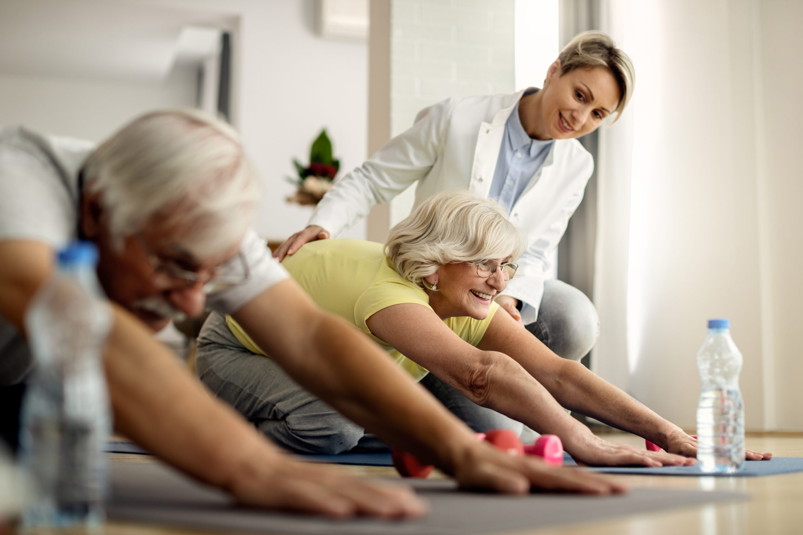 happy mature couple doing stretching exercises with help of phys